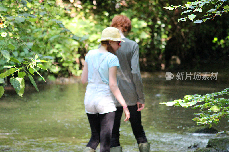 男孩和女孩在河边、林地里玩耍/涉水